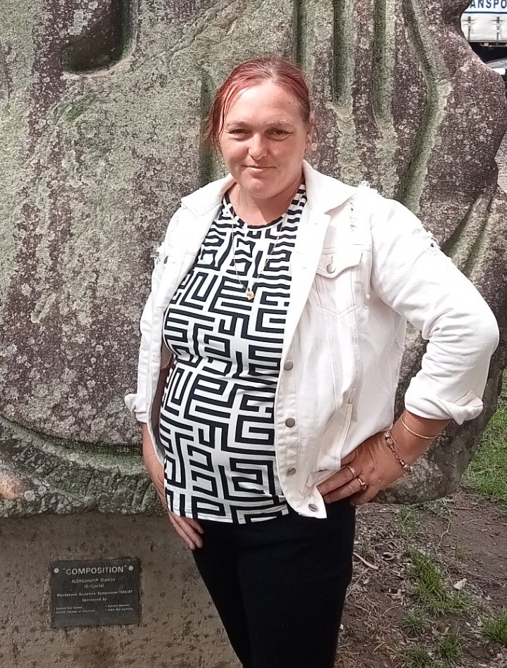 Natalie standing in front of a large tree trunk