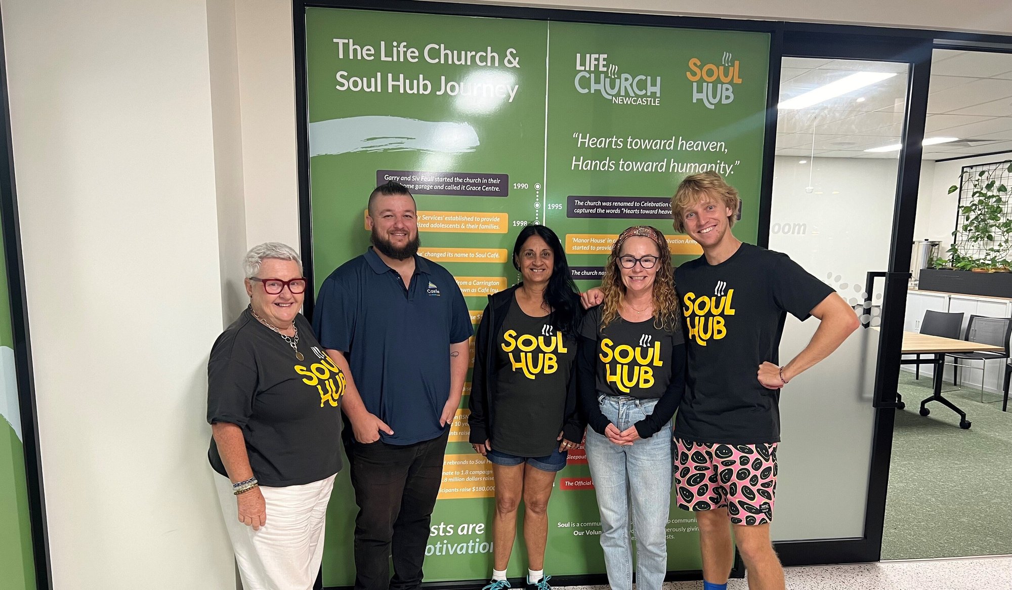 Margaret, Jay, Zana, Sally and Luke are smiling, inside Soul Hub's offices. Jay is wearing a navy polo and the rest black tees with the yellow 'soul Hub' logo.