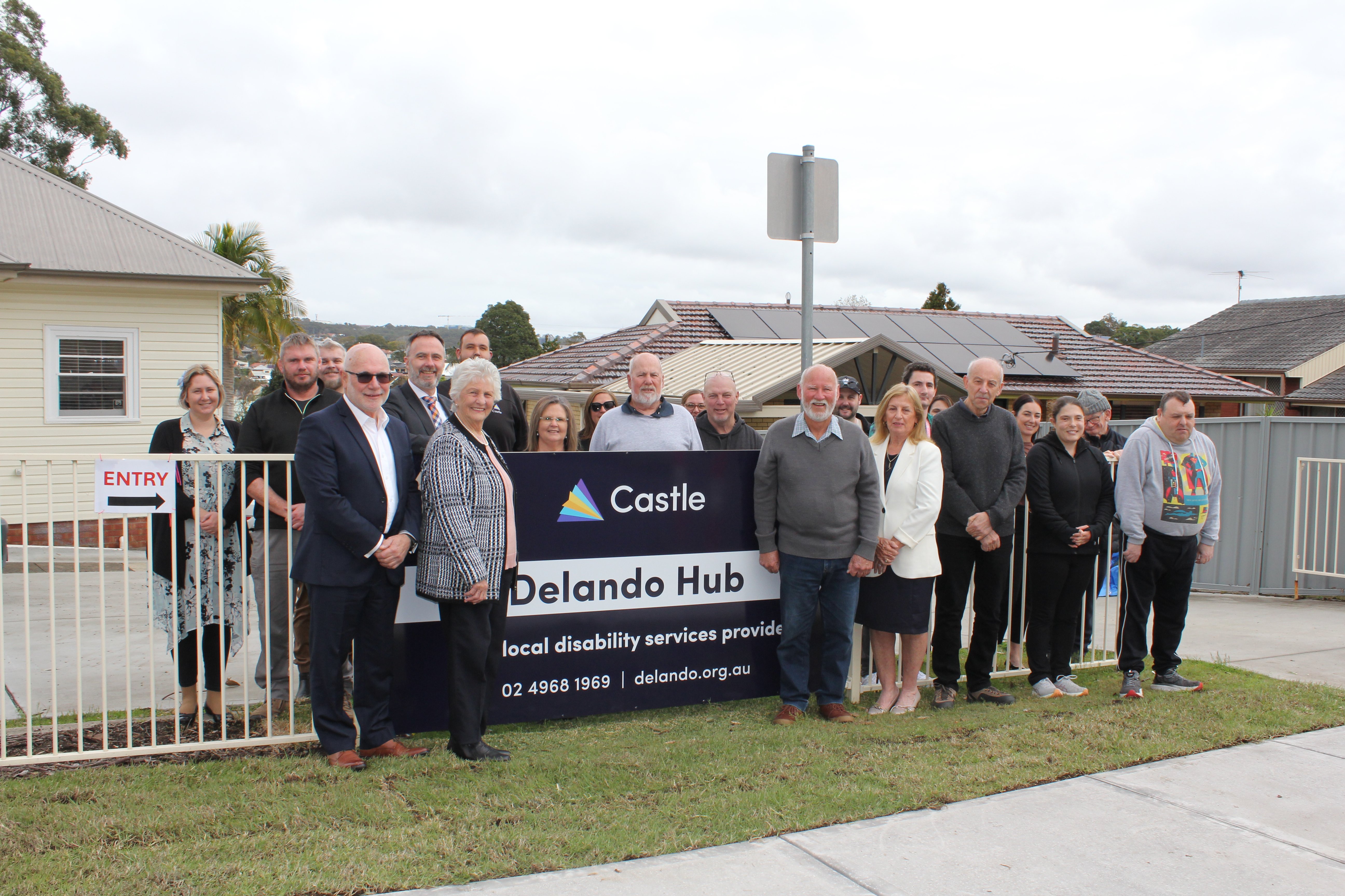 Group photo of Delando and Castle community members in front of new Delando Hub sign