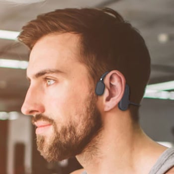 A man wearing earphones that fit around the outside of his ear, leaving his ears uncovered.